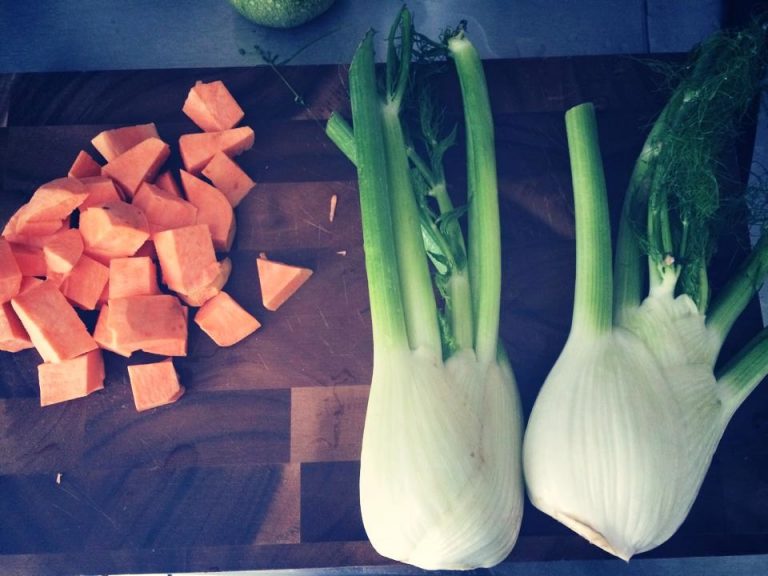 Two fennel bulbs next to diced sweet potato on a wooden board