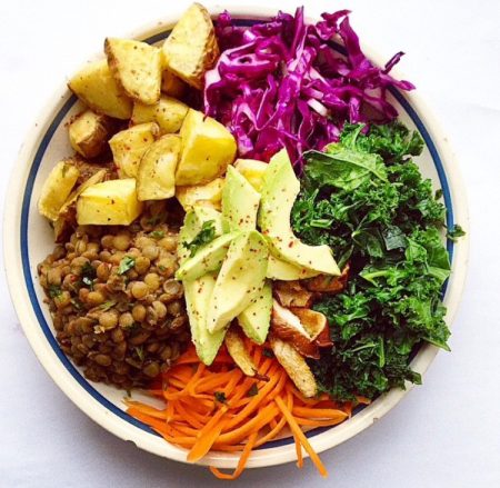 Plate with sections of roasted potatoes, red cabbage, kale, avocado, brown lentils and grated carrot