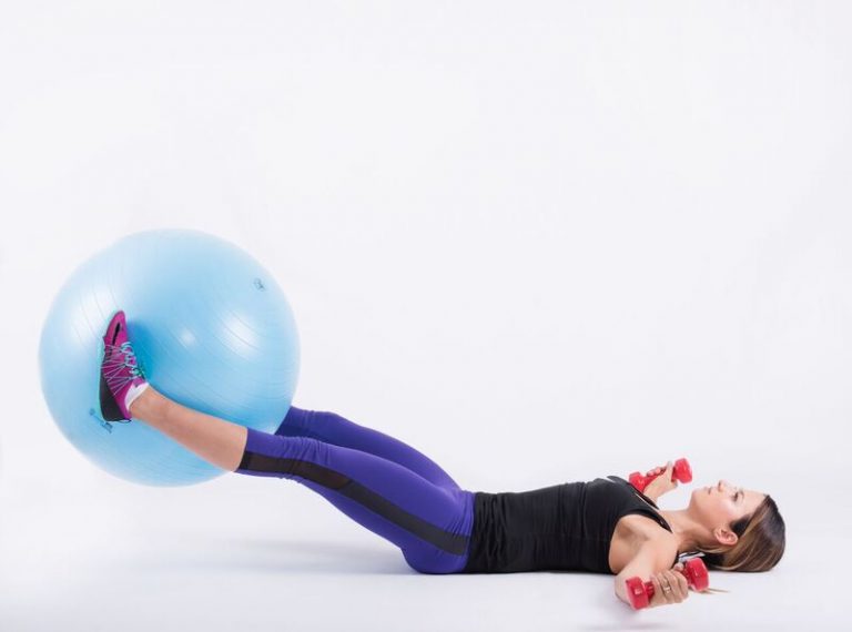 Legs and arms lowered towards the floor while holding the ball between the knees