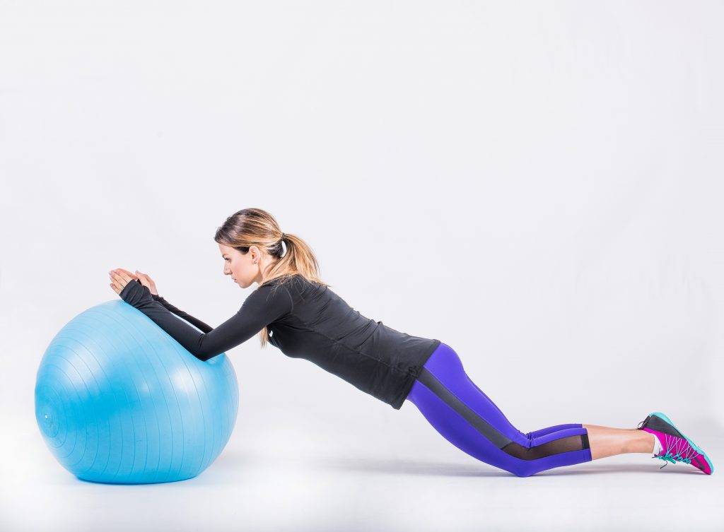 Kneeling with the ball rolled forward and the body extended in a straight line