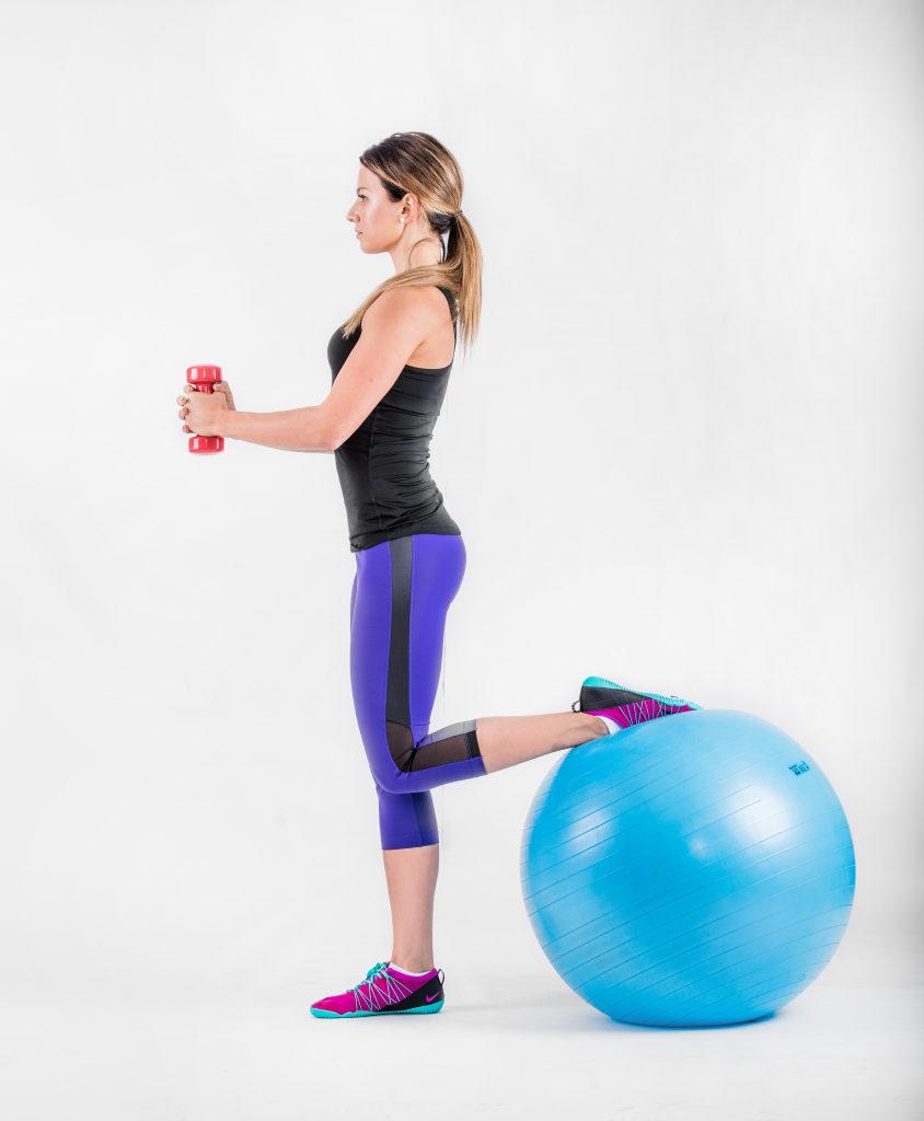 Standing with one ankle on the ball behind, holding a dumbbell, in the upright position