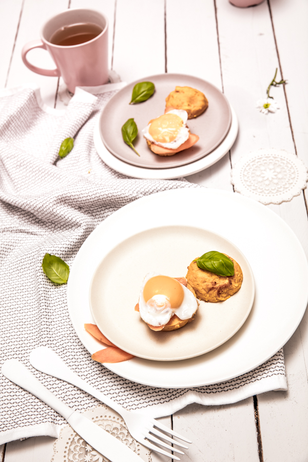 Vegetable burgers topped with a fried egg on white plates, with a mug of tea