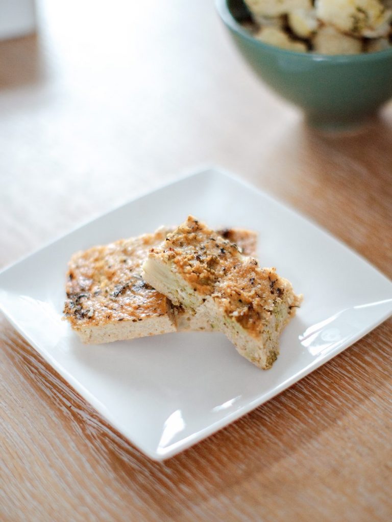 Two slices of baked millet frittata on a white square plate on a wooden table