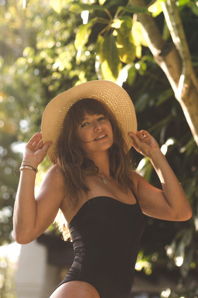 Anna Lewandowska holding the brim of her straw hat, outdoors in the sun