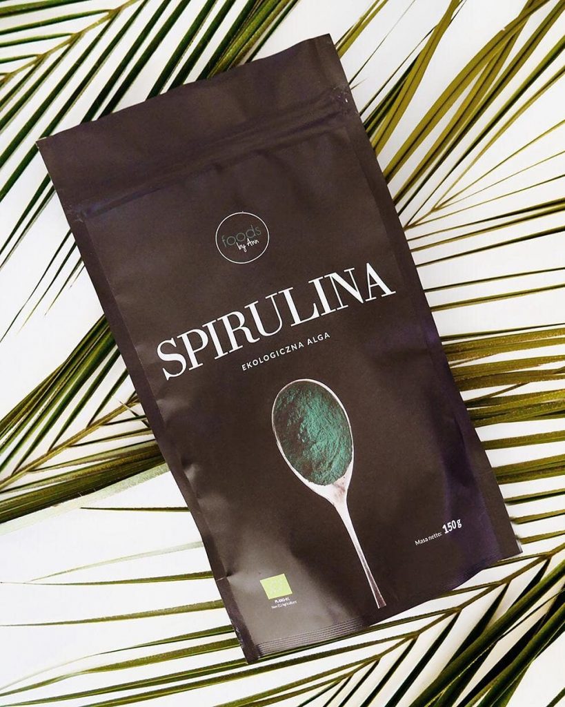 A pouch of Foods by Ann organic spirulina powder lying on a palm leaf