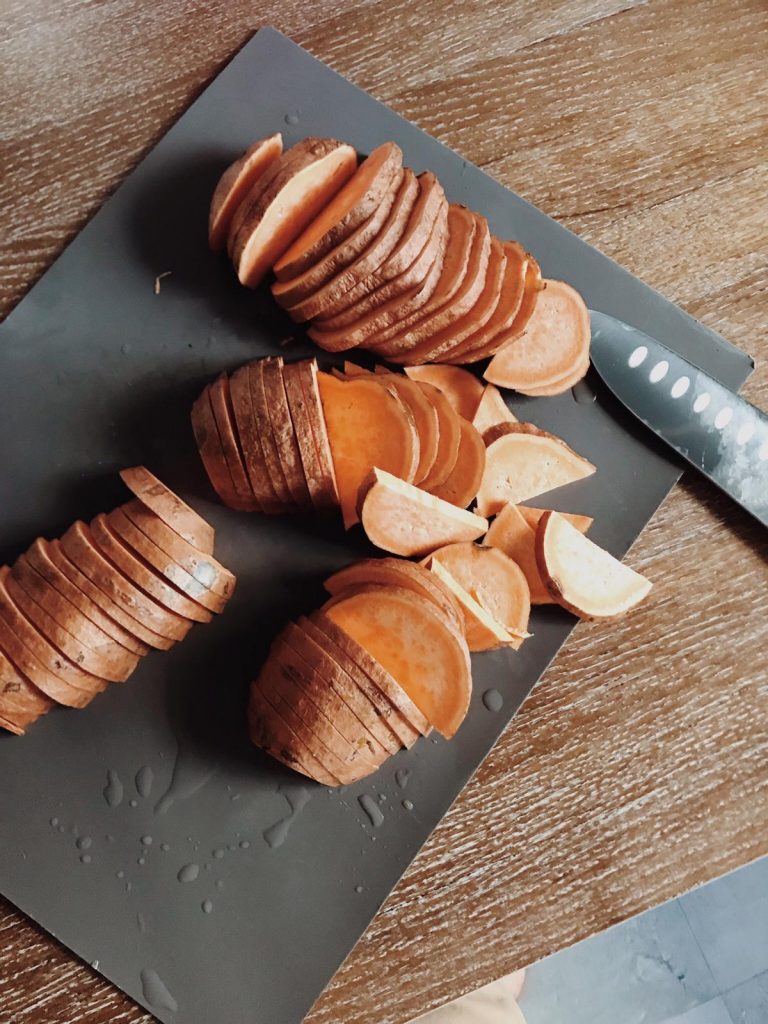Sweet potatoes sliced on a dark board with a knife
