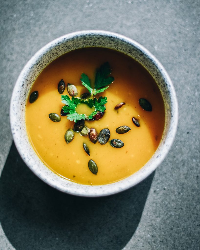 Pumpkin cream soup topped with pumpkin seeds and parsley, seen from above