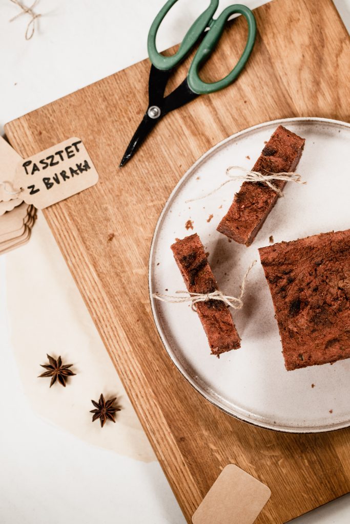 Slices of beetroot pate tied with string on a plate, on a wooden board with a handwritten label